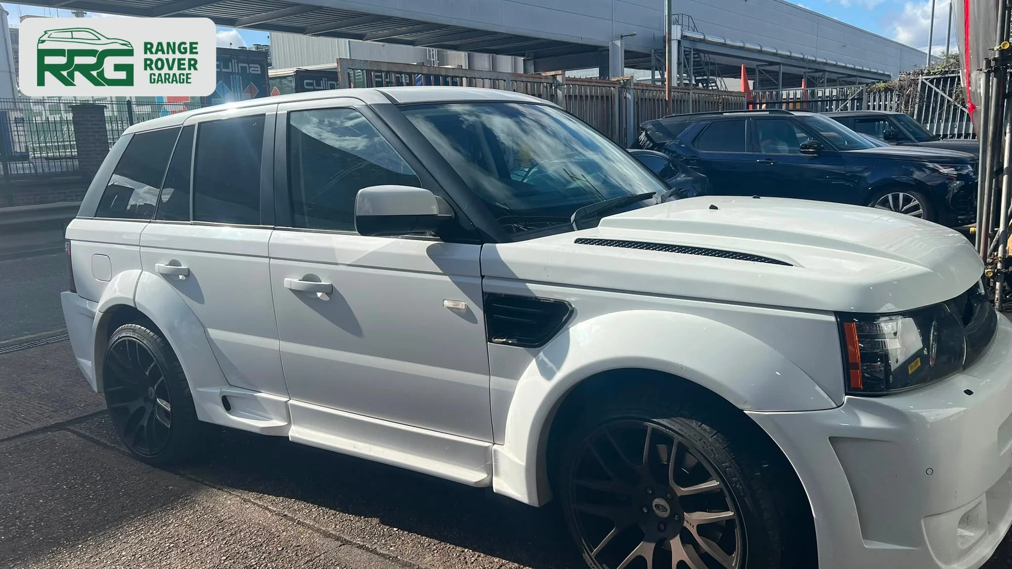 White Range Rover beside another vehicle outside the workshop