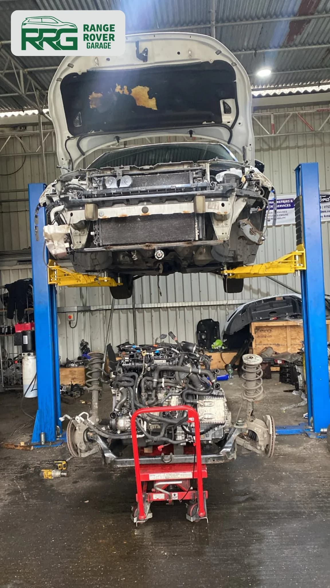 Vehicle raised on a lift above a removed engine in the workshop