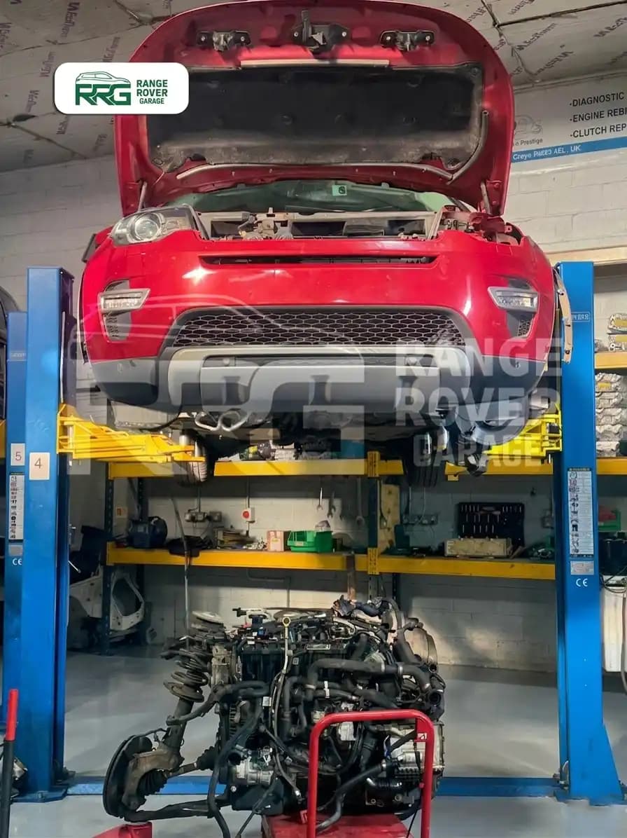 Red Range Rover on a lift with its removed engine below