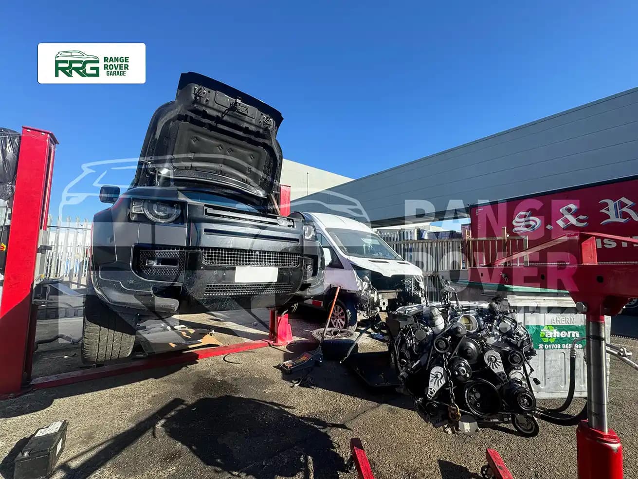 Range Rover with its bonnet open and a removed engine beside it