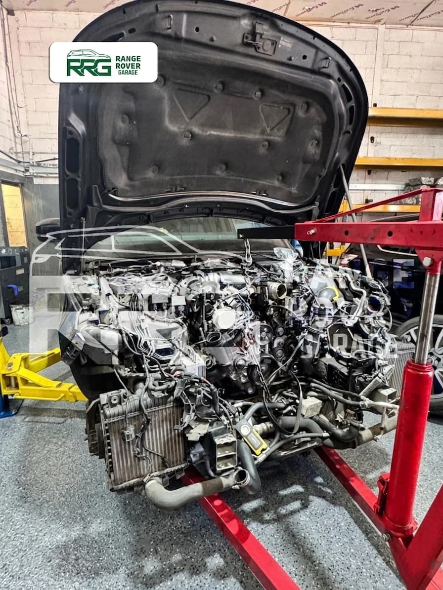 Removed engine on a stand in front of a Range Rover