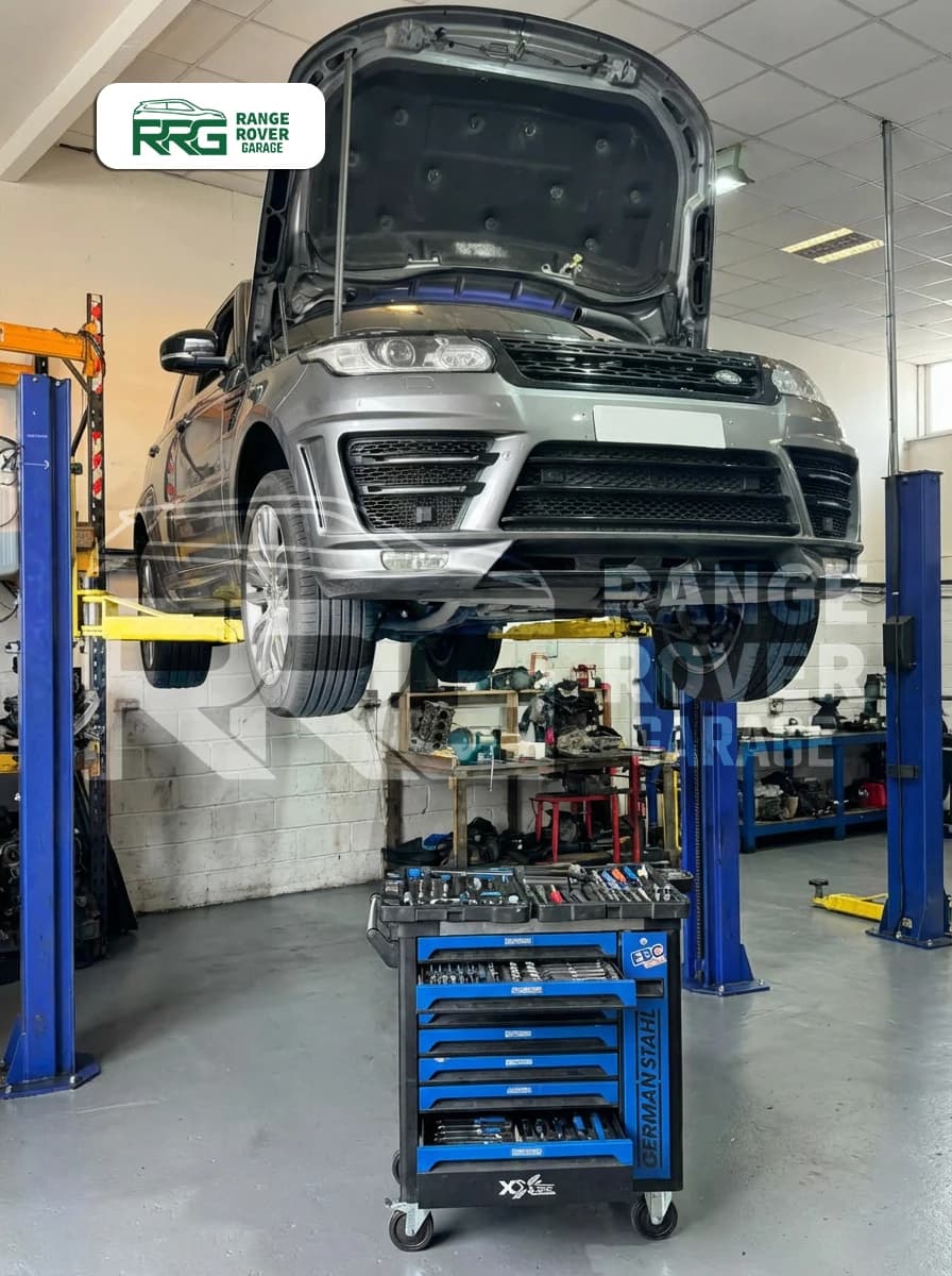 Range Rover raised above a tool trolley during engine repairs