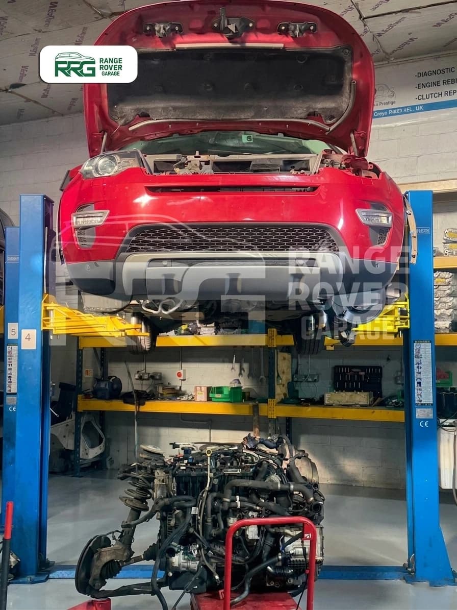 Red Range Rover on a workshop lift with its removed engine below